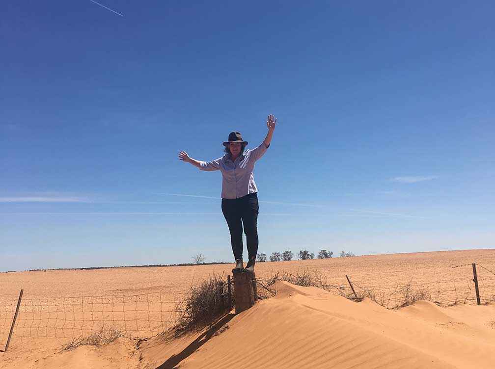 Suzie Jacobs, a member of the East Loddon Food Share Program Inc stands on a strainer post in front of a paddock that was in crop for the 2019 season at Meringur.