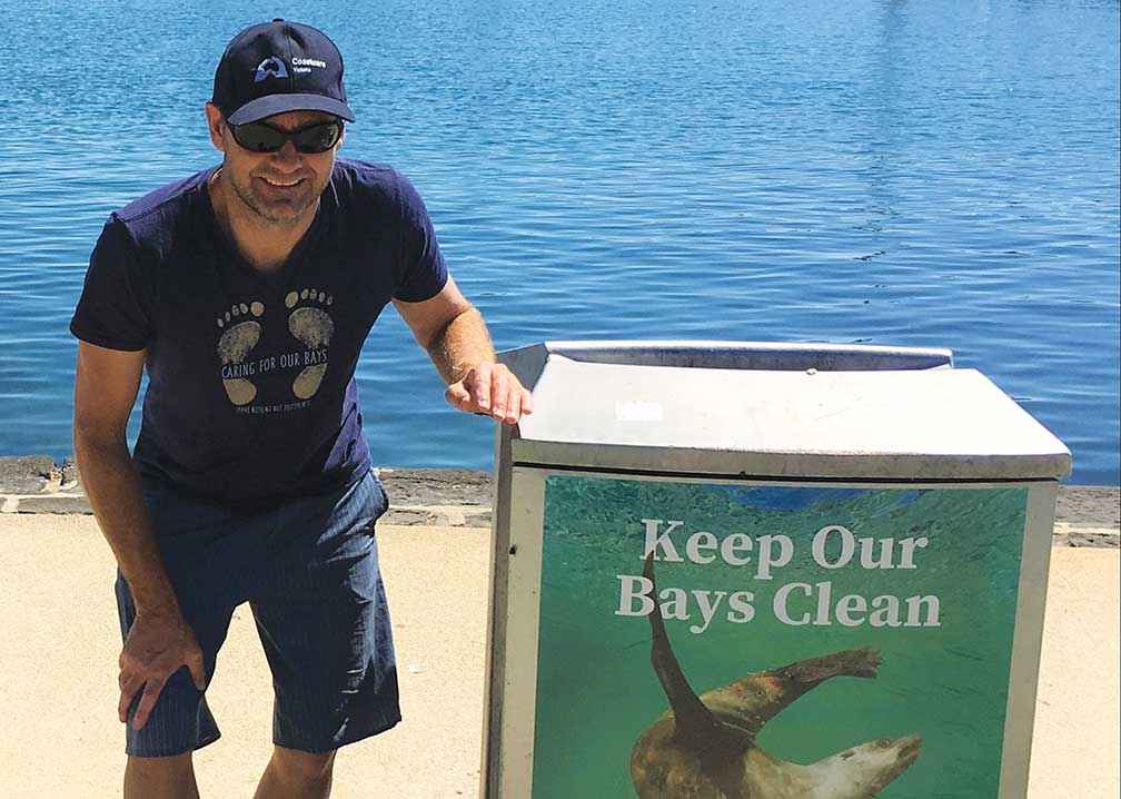 Matthew Crawley at Cunningham Pier in Corio Bay installing Caring For Our Bays bin wraps.