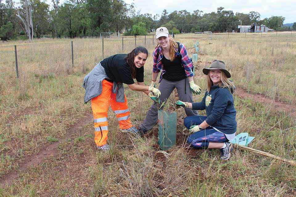 Young women from Illawarra Intrepid Landcare get their hands dirty on a revegetation project at Dubbo.